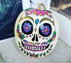 a painted pumpkin with flowers on it sitting next to a window sill in the day of the dead