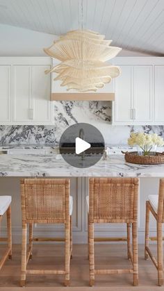 a kitchen with white cabinets and marble counter tops, along with two wicker chairs