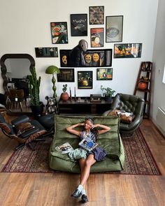 a woman sitting on top of a green couch in front of a wall filled with pictures