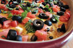 a casserole dish with olives, tomatoes and black olives