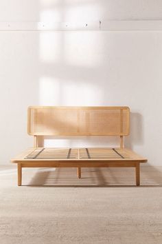 a wooden bench sitting in the middle of a room with white walls and flooring