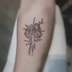 a cross and flowers tattoo on the left arm, which is also in black ink