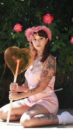 a woman sitting on the ground with a heart shaped lollipop in her hand