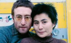 a man and woman are posing for a photo in front of a yellow wall with flowers on it