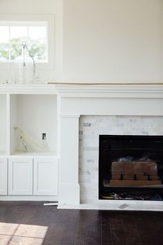 an empty living room with a fireplace and built - in bookshelves