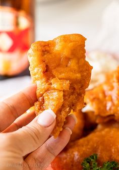 a hand holding up a piece of fried food