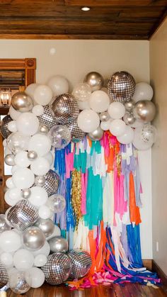 a room filled with balloons and streamers on the wall next to a wooden floor