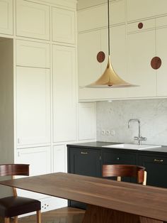 a modern kitchen with white cabinets and wooden table in the center, along with black chairs