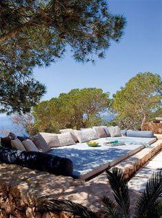 an outdoor seating area with pillows on the ground and trees in the backgroud