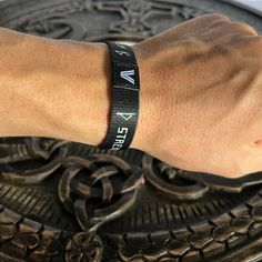 a person wearing a wristband with the word faith on it, sitting in front of a metal object