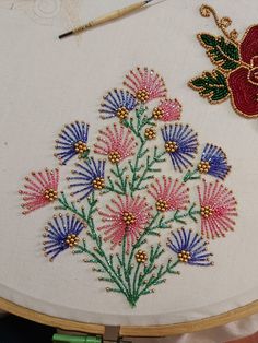 a close up of a embroidery on a piece of cloth with a needle and thread