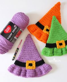 three crocheted witches hats next to a ball of yarn