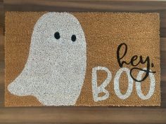 a door mat with a ghost on it that says, hey booy written in black ink