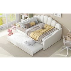 a white bed with pillows and blankets on it in a room next to a desk