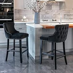 two black bar stools sit in front of an island