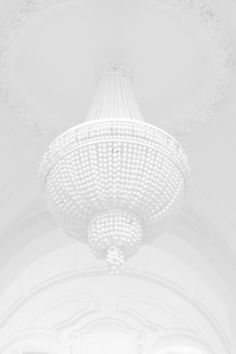 a large white chandelier hanging from the ceiling in a room filled with people