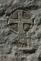 a cross carved into the side of a rock