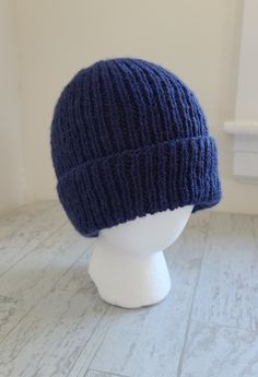 a white mannequin head wearing a blue knitted hat on top of it