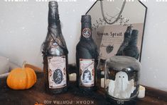 three halloween bottles sitting on top of a table next to a mirror and pumpkins