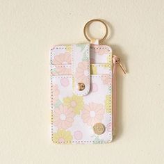 a pink and yellow flowered purse with a keychain hanging from the front