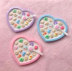 two heart shaped trays filled with cookies and candies on top of a pink blanket