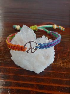 a bracelet with a peace sign on it sitting on top of a piece of rock