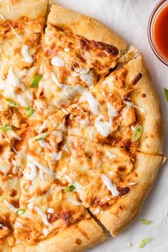 a pizza sitting on top of a table next to a cup of tea