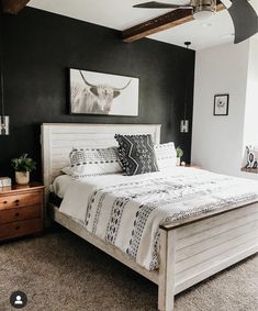 a bedroom with black walls and white bedding