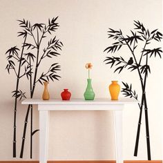 three vases are sitting on a table in front of a wall with bamboo trees