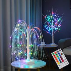 a table with a remote control on it next to a lit up tree in the living room