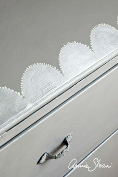 an old dresser has been painted with silver paint and scalloped trim on it