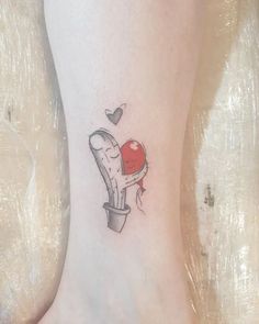 a small tattoo on the ankle of a woman's foot with a heart in it