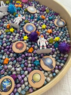 a bowl filled with lots of different types of magnets on top of purple rocks