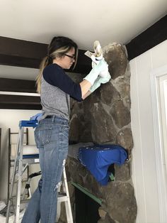 a woman standing on top of a ladder next to a rock