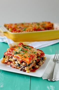 a white plate topped with lasagna next to a yellow casserole dish