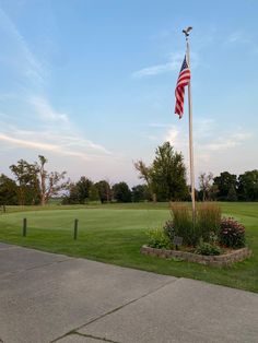 an american flag on a pole in the middle of a golf course