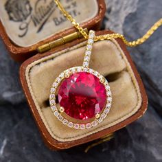 This sparkling pendant necklace is centered with a large round lab created ruby cut to brilliant perfection. Surrounding the ruby and climbing up the bale are thirty-six round brilliant cut diamonds, all set in 14k yellow gold. The pendant hangs from 14k yellow gold, 18 inch long cable chain with jump rings so it can also be worn at 16 and 17 inches as well. Luxury Lab-created Ruby Necklace Gift, Fine Jewelry Ruby Diamond Necklace Brilliant Cut, Ruby Necklace With Brilliant Cut, Luxury Red Diamond Round Necklace, Brilliant Cut Ruby Necklace In Round Shape, Luxury Red Diamond Necklace, Luxury Red Round Diamond Necklace, Fine Jewelry Red Diamond Necklace With Brilliant Cut, Yellow Gold Ruby Necklace With Prong Setting