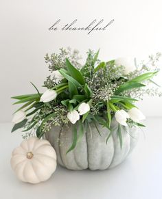 a white pumpkin filled with flowers and greenery