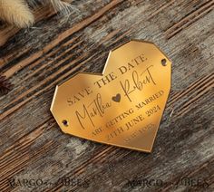 a gold save the date magnet on top of a wooden table next to some feathers