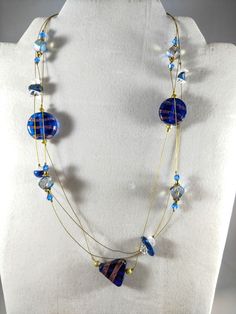 Drape the feeling of elegance around your neck with this lovely necklace. Beautiful Blue & Gold lampwork beads suspended on a Gold filament wire with a toggle clasp. This beautiful triple strand floating necklace would be perfect for a casual night out on the town. Fashioned in Blue and Gold it would dress up a cute denim outfit. Order Now! https://www.etsy.com/shop/jbbutterflydesigns Elegant Czech Glass Long Necklaces, Double Strand Czech Glass Faceted Bead Necklaces, Double Strand Czech Glass Necklaces With Faceted Beads, Double Strand Czech Glass Necklace With Faceted Beads, Blue Czech Glass Necklaces With Wire Wrapped Detail, Blue Single Strand Murano Glass Beaded Necklace, Elegant Multi-strand Adjustable Crystal Necklaces, Elegant Adjustable Multi-strand Crystal Necklaces, Multi-strand Necklaces With Spacer Beads For Jewelry Making