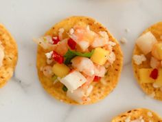 small crackers with fruit and veggies on them sitting on a white surface