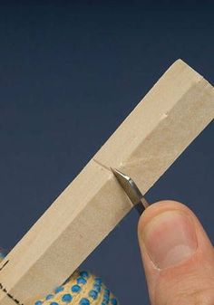 a person holding a pair of scissors in front of a piece of wood with blue dots on it