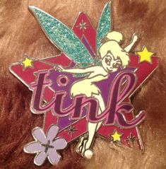 a pin with the word tink on it and a flower in front of it