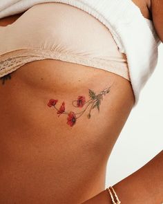 a close up of a woman's stomach with red flowers on the side and behind her