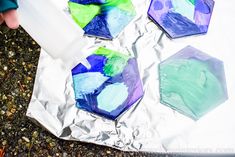 the child is painting on foil with different colors and shapes to make them look like he's holding something in his hand