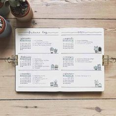 an open planner with plants and potted plants next to it on a wooden table