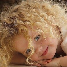 a close up of a child laying on the ground with her hands under her chin