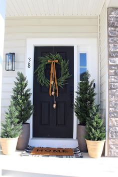 the front door is decorated with evergreen wreaths