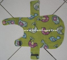 a green bib with blue and pink birds on it, sitting on a tile floor