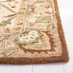 a brown and green rug on the floor with white wood planks in the background